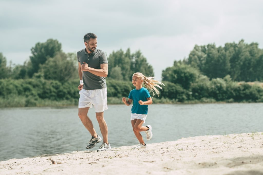 far och dotter springer på stranden